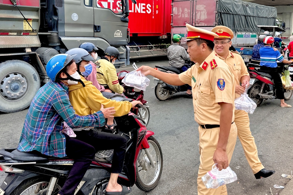 Cán bộ CSGT nhiệt tình hỗ trợ người dân di chuyển trên xe máy bằng những phần quà nhỏ như nước uống, mang lại cảm giác ấm áp trên đường về quê ăn Tết.