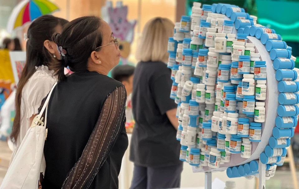 Người tham dự chăm chú quan sát mô hình được tạo từ hàng trăm lọ thuốc ARV, biểu tượng cho hành trình điều trị và sống khỏe của người có HIV. Ảnh: BTC.